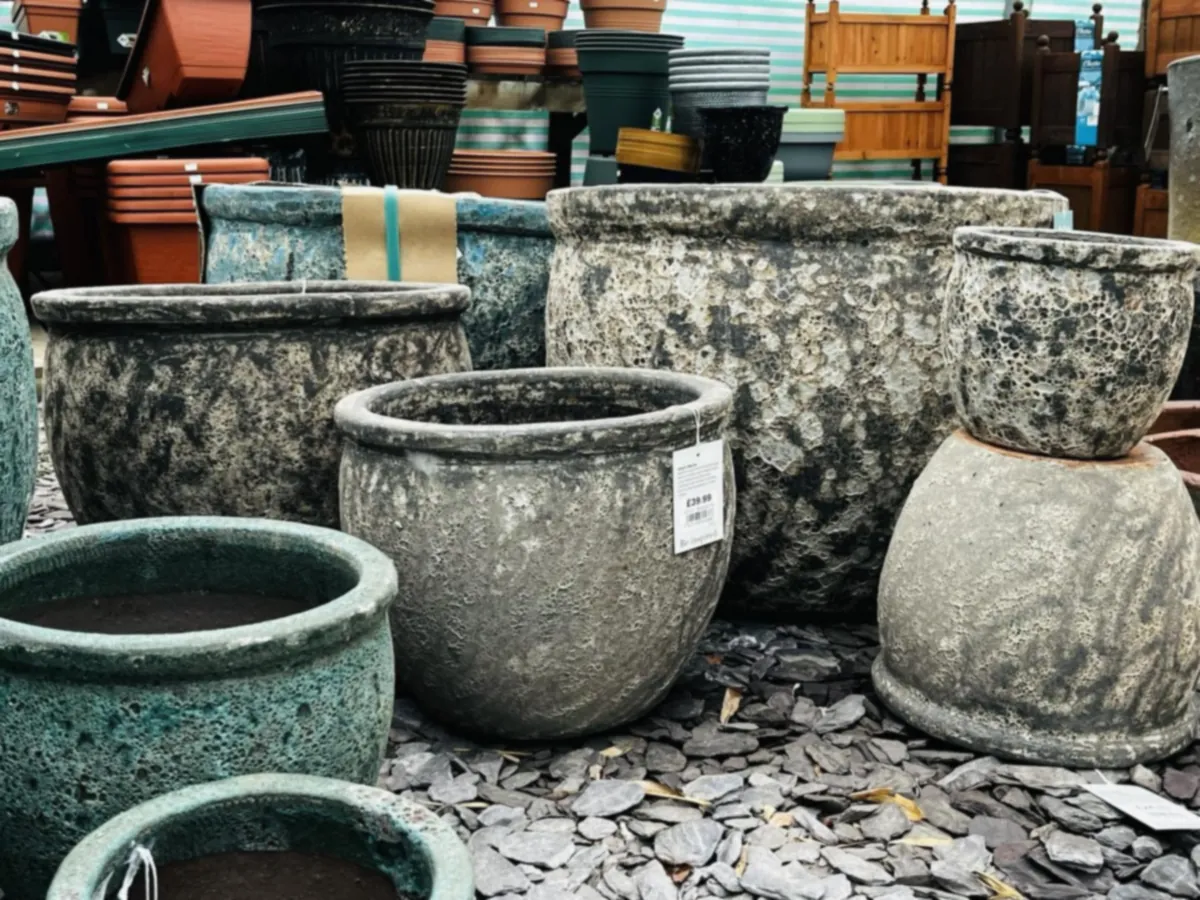 Weathered glazed stone planters on slate chippings at Westfield Nurseries, Whittlesey